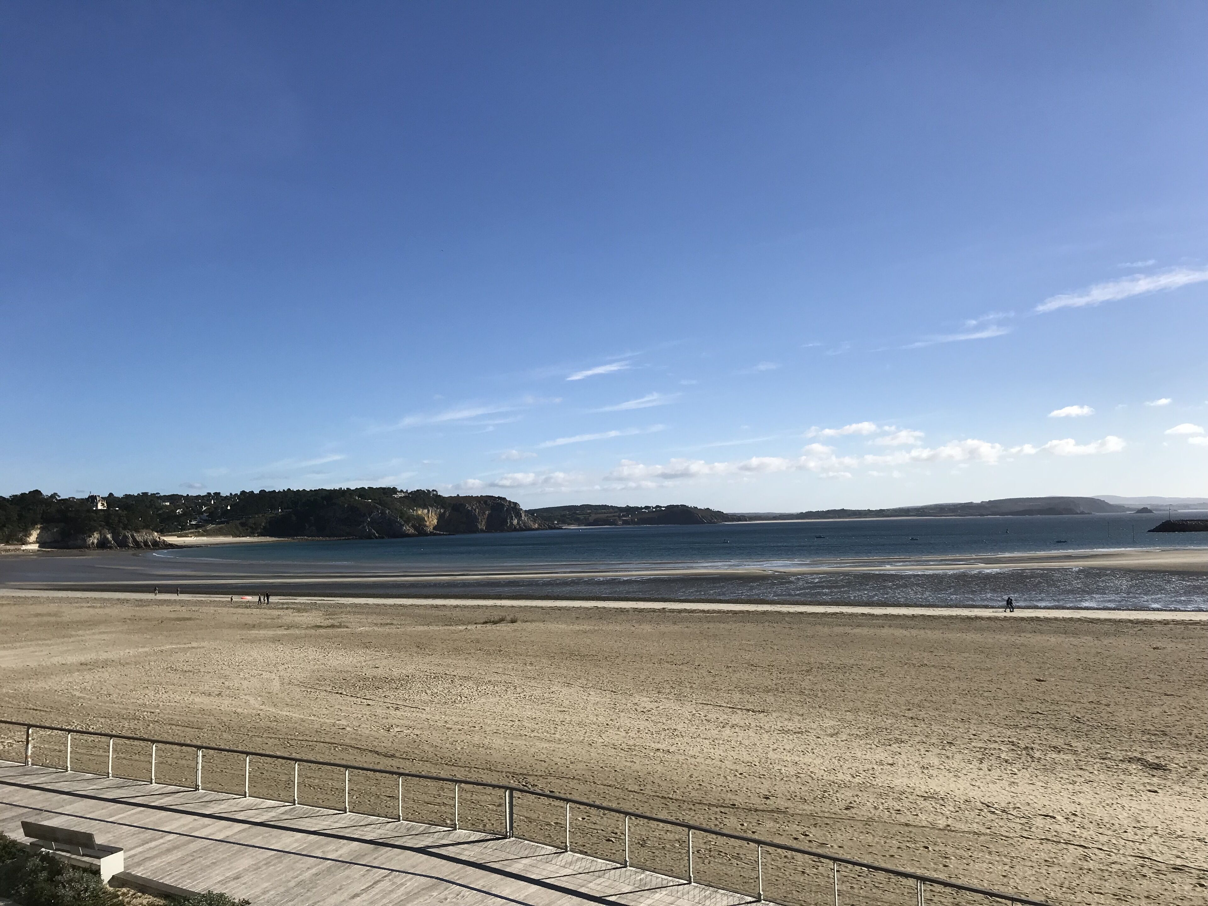 A beach with a wooden walkway and a metal railing.