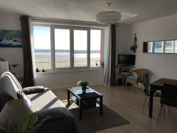 Un salon avec un canapé, une table basse, un téléviseur et une vue sur la plage.