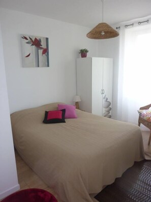 Une chambre à coucher avec un lit, une armoire, une lampe suspendue, une chaise et un tableau au mur.