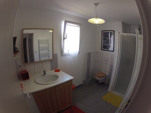 Une salle de bain équipée d’un lavabo, d’un miroir, de toilettes et d’une douche.