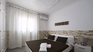 Ein Schlafzimmer mit einem Bett, einem Nachttisch, einer Lampe und einer Wand-Klimaanlage.