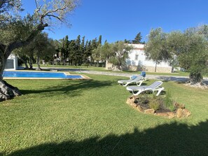 A pool area with lounge chairs and a stone building in the background.