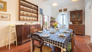 Comedor con una mesa dispuesta para cuatro, armarios de madera, una escalera y un escurreplatos fijado a la pared.