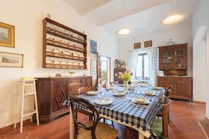 A dining room with a table set for four, wooden cabinets, a ladder, and a wall-mounted dish rack.