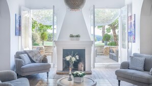 Un salon avec une cheminée, deux canapés, une table basse et une vue sur l’extérieur.