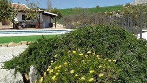 Une maison moderne avec une piscine, entourée de verdure et sous un ciel dégagé.