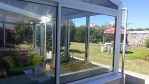 A conservatory with a view of a grassy yard, a table, and chairs. - SPACIOUS RENTAL FOR 10/12 PERS: 2 EQUIPPED KITCHENS; GARDEN CLOS AND VERANDA (Primelin)