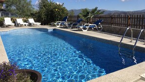 A swimming pool with clear blue water, surrounded by lounge chairs and a wooden fence. - Tipical Country Side house whith nice landscapes and pool (Fafe)