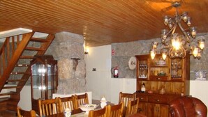A dining area with a wooden table, chairs, a chandelier, and a stone wall. - Tipical Country Side house whith nice landscapes and pool (Fafe)