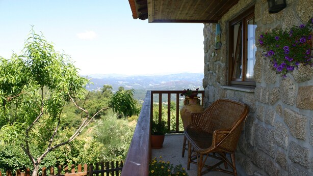 A stone building with a balcony, wicker chairs, and potted plants. - Tipical Country Side house whith nice landscapes and pool (Fafe)