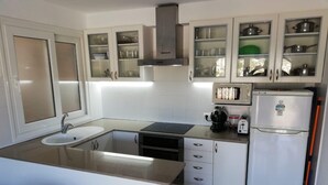 Una cocina moderna con armarios blancos, horno empotrado, microondas y pileta.