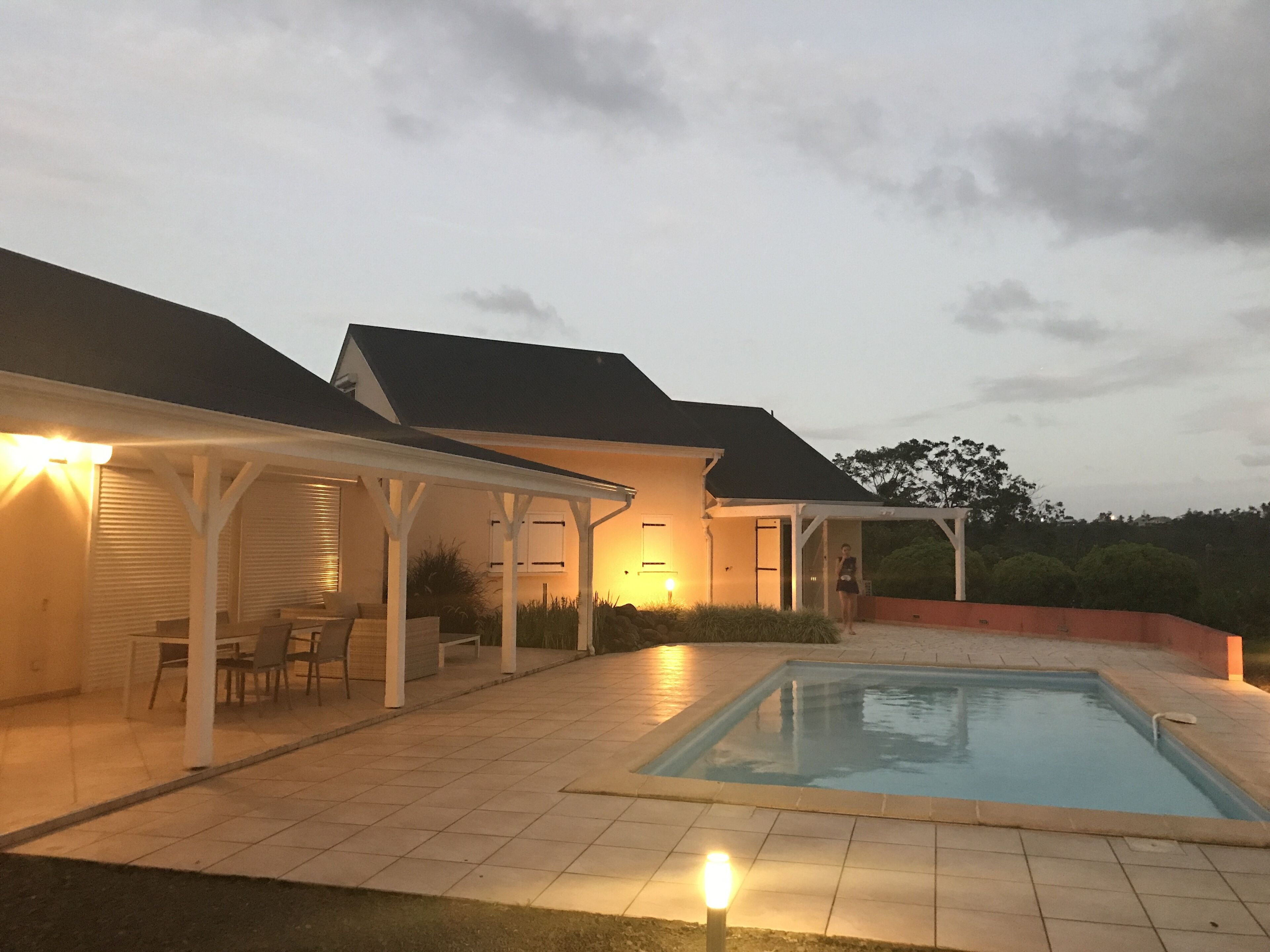A covered patio area with a pool, outdoor seating, and a well-lit entrance.