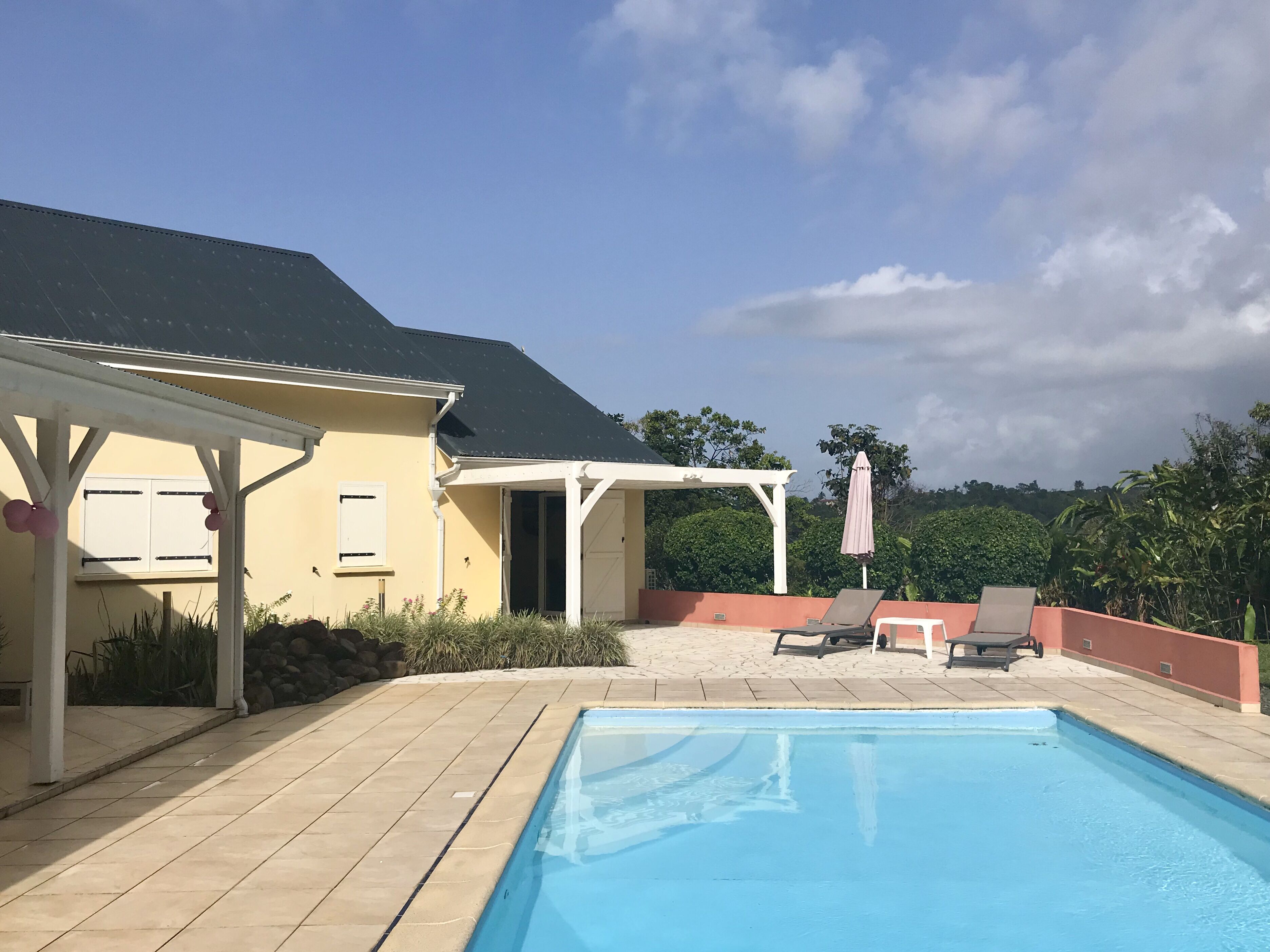 A swimming pool with lounge chairs and a covered patio area.