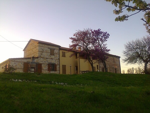 A stone building with a yellow facade, a door, and a window. - In the Conero Park, with the sea below the house (Ancona)