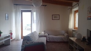 Ein gemütliches Zimmer mit einer Couch, einem kleinen Tisch mit Lampe und einem an der Wand montierten Feuerlöscher.