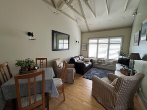 A cozy living room with a dining table, chairs, a sofa, and a television.