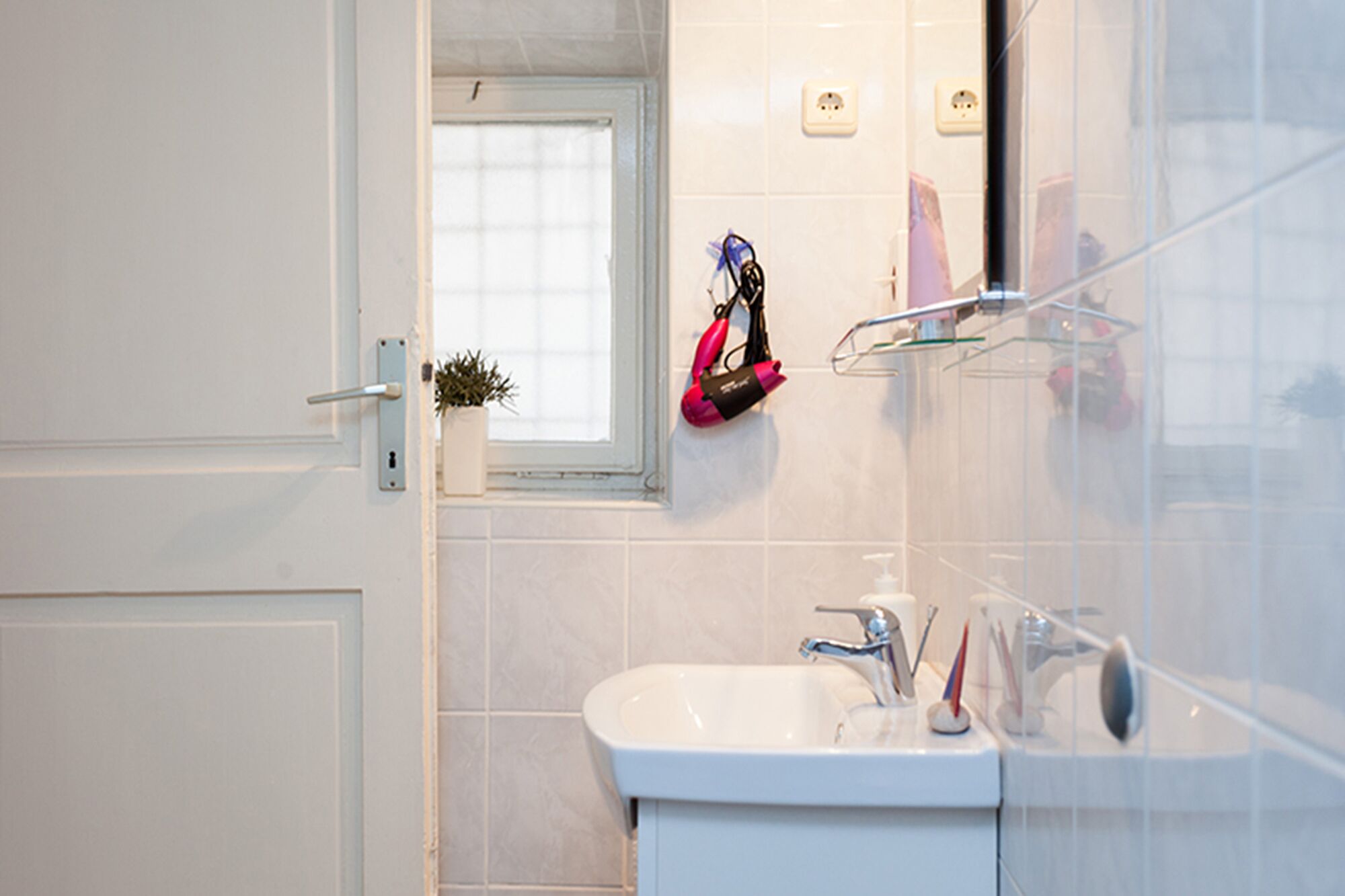 A bathroom with a white sink, mirror, and a window with blinds.