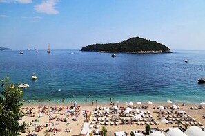 A beach with sun loungers and umbrellas, boats in the water, and a small island in the distance. - Do you want to fully enjoy Old Town ? Mara apt quiet and next to citty walls (Dubrovnik)