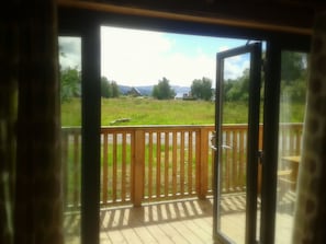 Enjoy a serene view from your deck, surrounded by a grassy area and a mountain range.