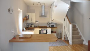 A kitchen with a wooden countertop, a microwave, and a hanging light fixture. - Cottage In Prestleigh, Somerset, England (Prestleigh)
