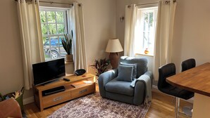 A living room with a sofa, a TV, a lamp, and a dining table. - Cottage In Prestleigh, Somerset, England (Prestleigh)