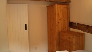 Un dormitorio con un armario de madera, una puerta blanca y una cama con una toalla blanca doblada.