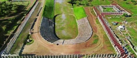 Vista aérea de un estadio con una pista central, gradas para espectadores y zonas verdes circundantes.