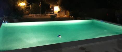 Ein Schwimmbecken bei Nacht, in dem sich ein einzelnes Objekt auf der Wasseroberfläche treibt.