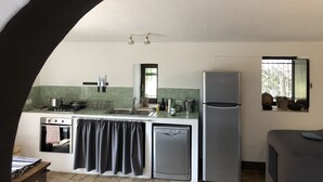 Una cocina con una isla central, estufa, horno, pileta y refrigerador.