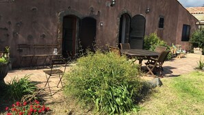 Un edificio rústico con un patio amueblado y plantas en macetas.