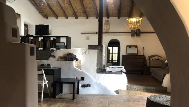Un interior rústico con chimenea de piedra, techo de madera y una zona de estar acogedora.