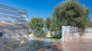 A stone wall with a plaque, a white fence, and a tree in a courtyard. - Nereid Villa, with Heated Pool & Heated SpaWhirlpool, BBQ, Impeccable SeaViews (Rethymno)
