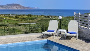 A poolside area with two lounge chairs, a clear view of the sea, and a mountainous landscape in the background. - Nereid Villa, with Heated Pool & Heated SpaWhirlpool, BBQ, Impeccable SeaViews (Rethymno)