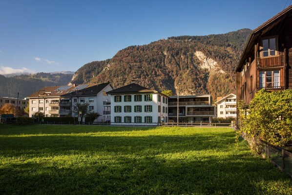 Una hilera de edificios tradicionales de estilo europeo, con balcones, frente a un paisaje montañoso.