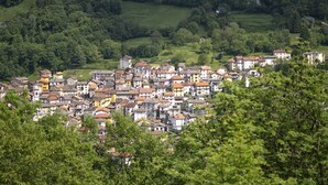 A densely packed town with closely built houses, surrounded by lush greenery and hills in the background. - BETWEEN THE FOREST AND THE LAKE (Schignano)
