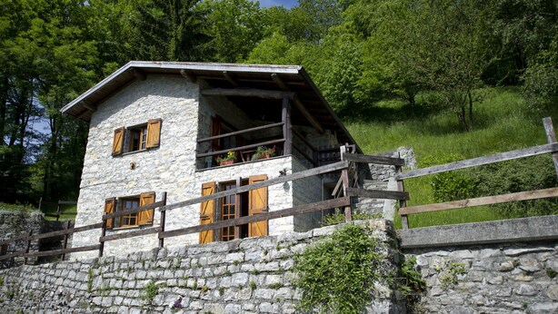 A stone house with wooden shutters, a balcony, and a wooden fence. - BETWEEN THE FOREST AND THE LAKE (Schignano)