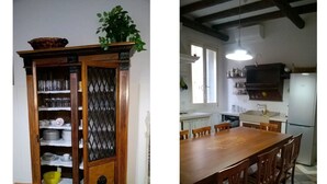 A dining area with a wooden table and chairs, a cabinet with glass doors, and a kitchen area with a refrigerator and sink.