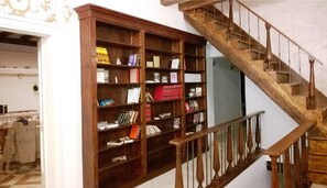 Staircase leads to an upper level, adjacent to a bookshelf with a collection of books and decorative items.