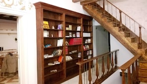 Staircase leads to an upper level, adjacent to a bookshelf with a collection of books and decorative items.