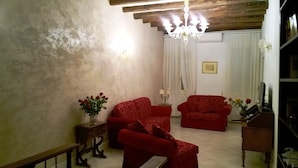 A living room with two red armchairs, a wooden coffee table, a chandelier, and a vase with flowers.