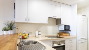 A modern kitchen with white cabinets, a stainless steel sink, a microwave, and a refrigerator. - Total Relax Apartment (Porís de Abona ( Arico ))