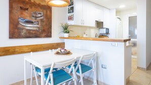 A modern kitchen with white cabinets, a wooden countertop, and a hanging light fixture. - Total Relax Apartment (Porís de Abona ( Arico ))