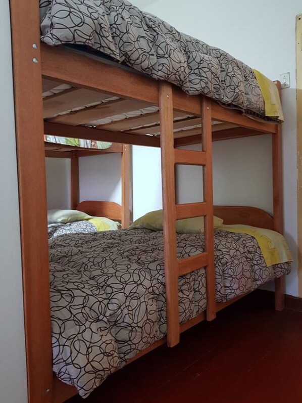 A bunk bed with a wooden frame, patterned bedding, and a ladder. - The Embassy - Backpackers (Cusco)