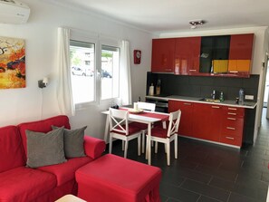 A modern living room with a red sofa and a dining area with a white table and chairs.