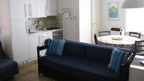 A compact kitchen with white cabinets, a washing machine, and a dining area with a table and chairs. - Monterosso al Mare Studio - Old Town - Cod. CITRA 011019-LT-0270 (Monterosso Al Mare)