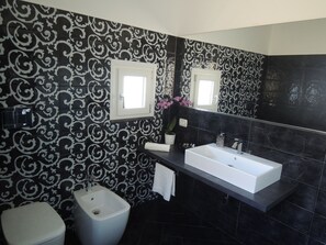 Une salle de bain moderne avec des carreaux noirs et blancs formant un motif, un lavabo blanc et un bidet.