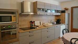A modern kitchen with stainless steel appliances, wooden cabinets, and a tiled backsplash. - Nice house with view (Vero)