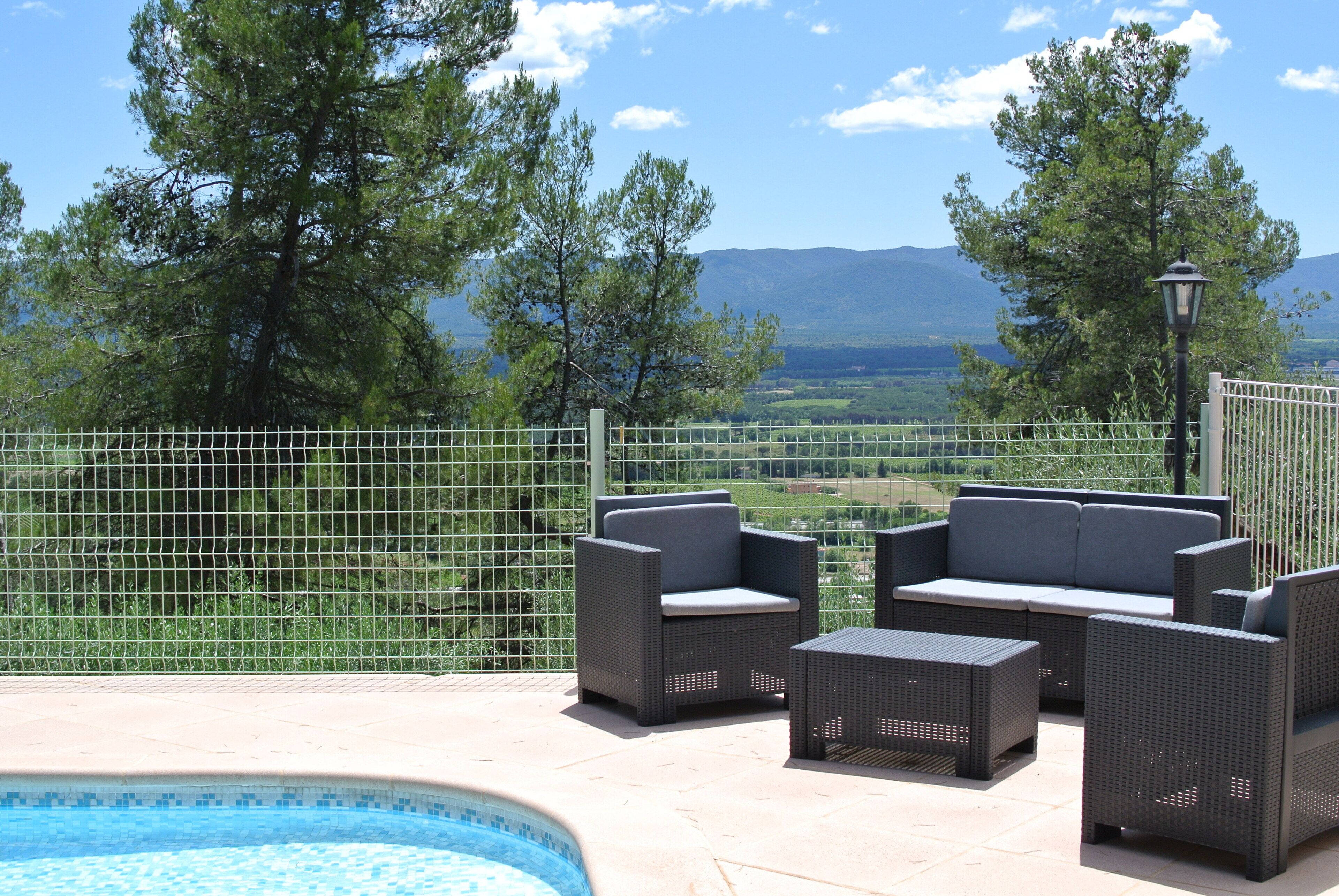 A poolside area with wicker furniture and a view of mountains.