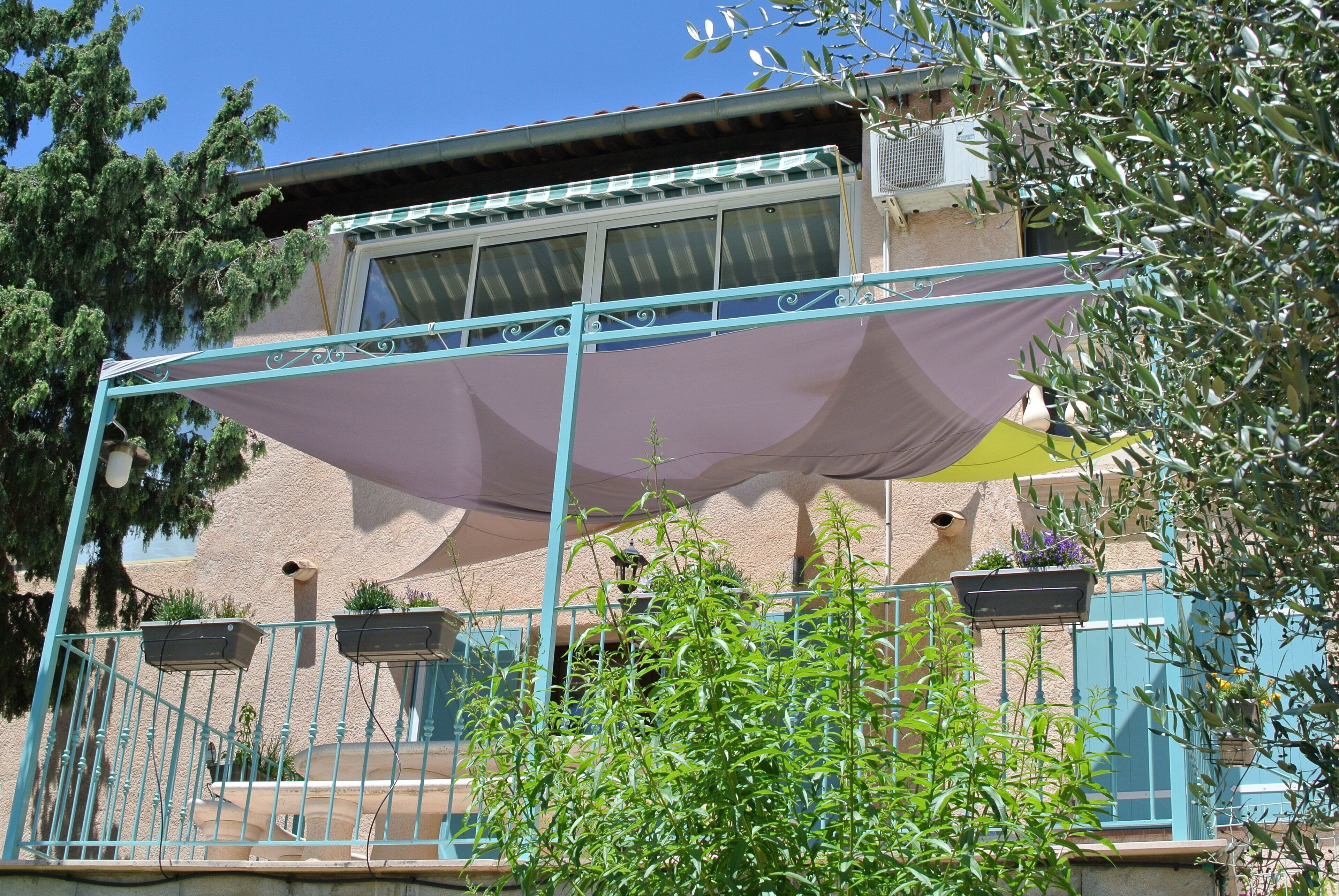 A building with a balcony, a covered area, and potted plants.