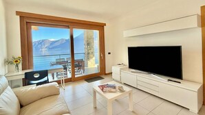 Un salon moderne doté d’un grand téléviseur, d’un canapé, d’une table basse et d’un balcon offrant une vue sur les montagnes.